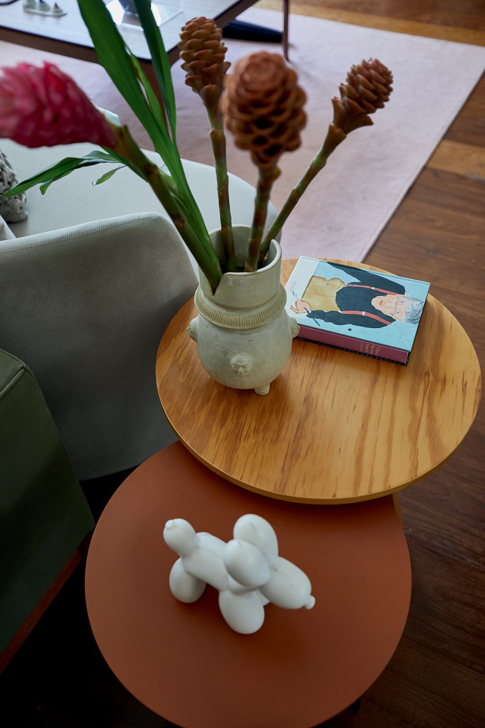 No living, detalhe com mesas laterais da Tok&Stok (laranja) e da Oppa Design (madeira), e, sobre a última, vaso Catimbó, da Potira Pottery, no Casa Vogue Living Market — Foto: Deco Cury