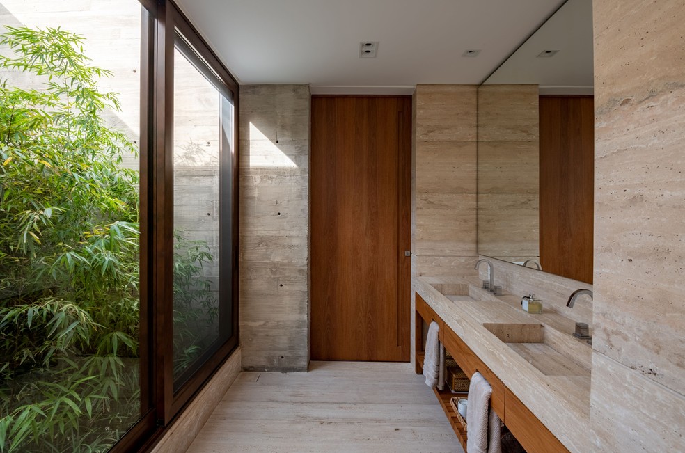 Com duas cubas, o banheiro social conta com uma bancada ampla e tem vista para o jardim — Foto: Fávaro Jr.