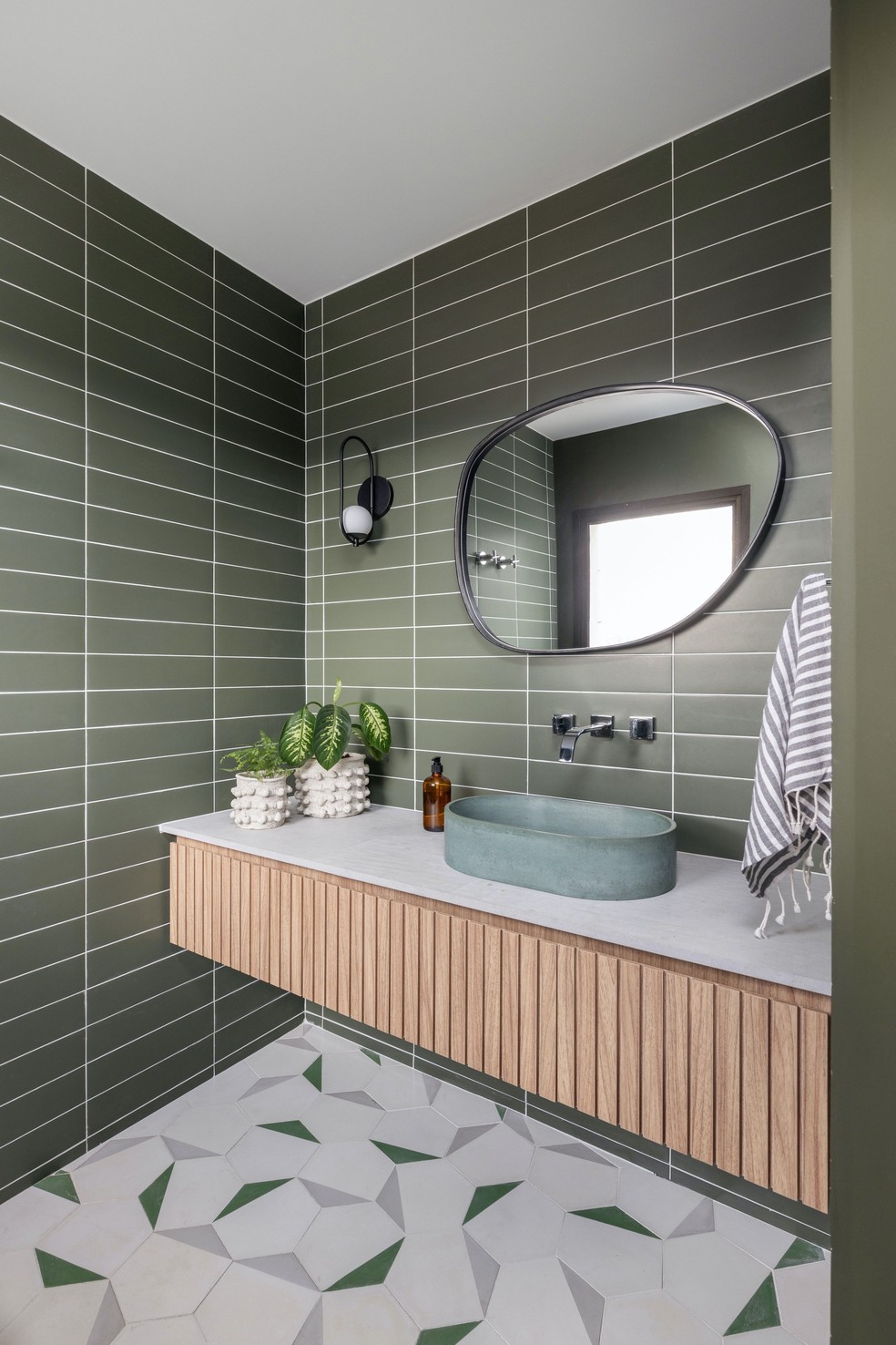 No lavabo, a cor verde também é predominante e está presente no revestimento das paredes e no piso de ladrilho hidráulico — Foto: Maura Mello