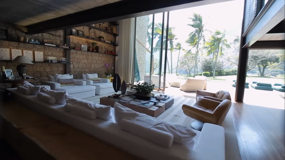 A sala de estar tem acesso à piscina e ao jardim — Foto: Reprodução/YouTube @@CRISTIANOPIQUET