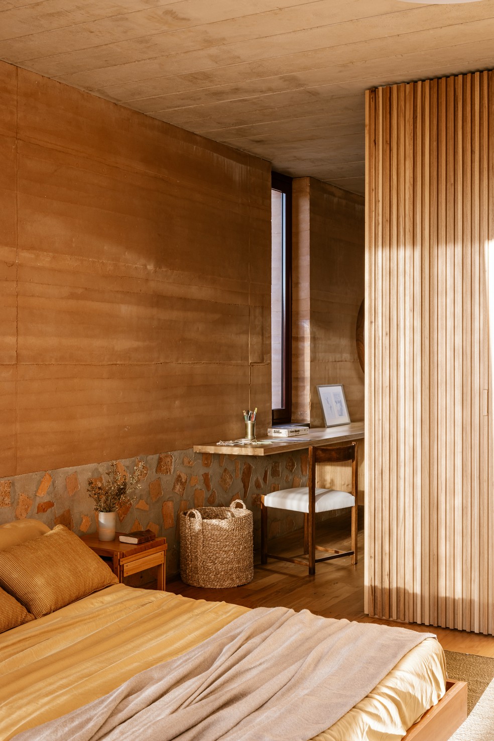 Concreto ciclópico atua como cabeceira, enquanto a taipa de pilão fornece conforto térmico ao quarto em projeto assinado pelo F.Studio, em Botucatu — Foto: Fran Parente