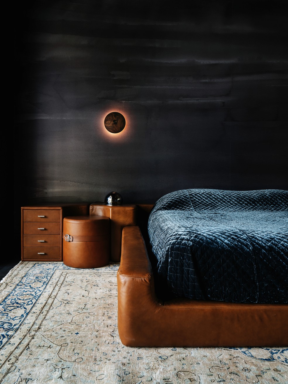 Em tons de marrom, revestimento da cama baixa em couro e mesa de cabeceira se complementam na decoração do quarto — Foto: Chase Daniel