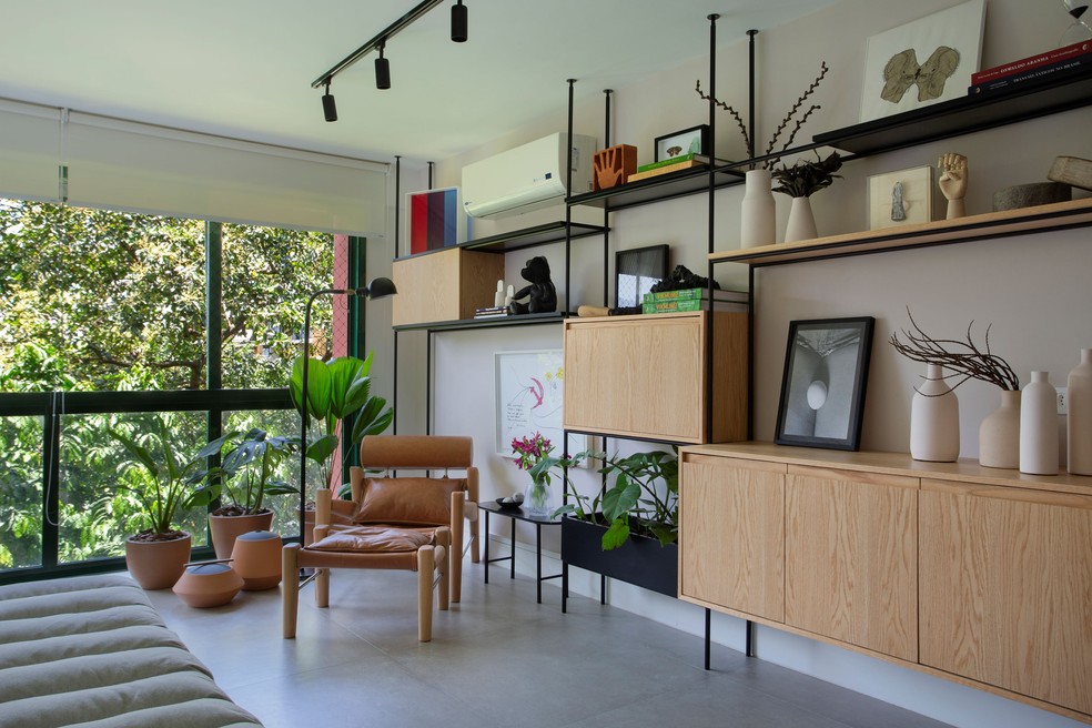 A área social integrada deste apartamento ganhou uma estante bastante minimalista de ferro e madeira — Foto: Denilson Machado/MCA Estúdio