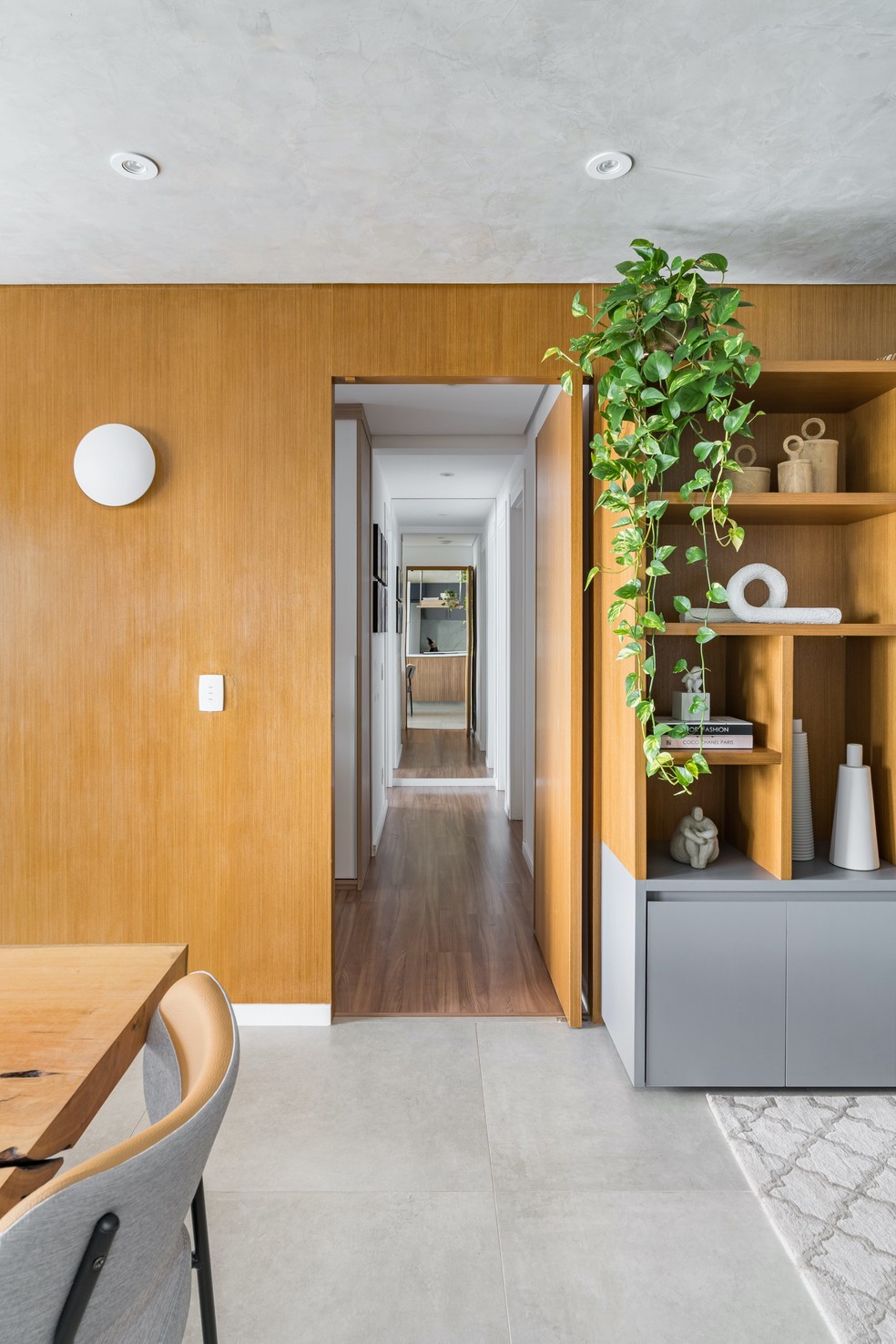 A folha de madeira natural também camufla a porta que dá acesso à área íntima — Foto: KL Fotografia
