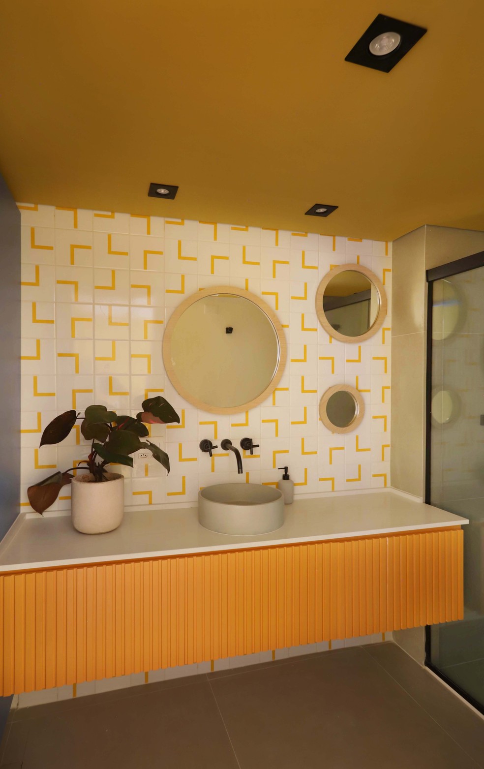 No lavabo, o mostarda toma o teto, a bancada em marcenaria e aparece também nos detalhes dos azulejos — Foto: Mariana Orsi