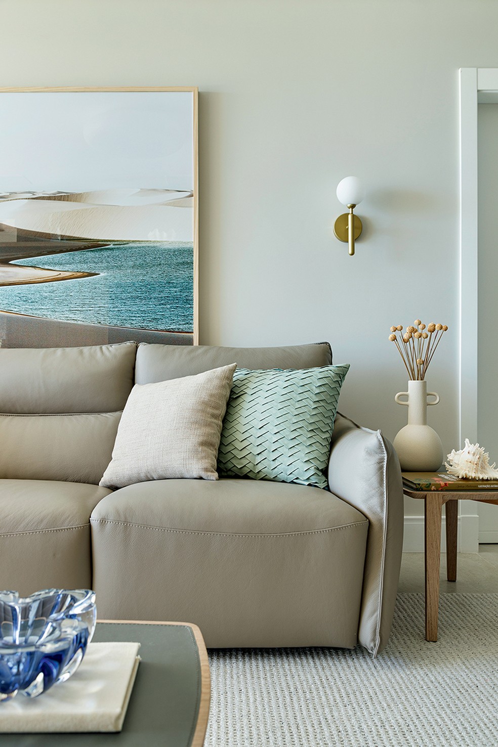 Detalhe da sala de estar de cores neutras, decorada com sofá de couro natural, da Natuzzi — Foto: Mariana Boro/Divulgação