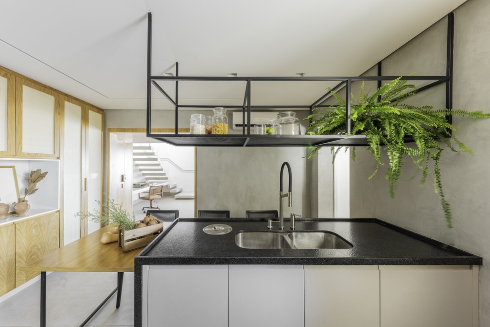 Ainda no primeiro andar, a cozinha exibe bancada com granito preto e armários feitos sob medida — Foto: Guilherme Pucci