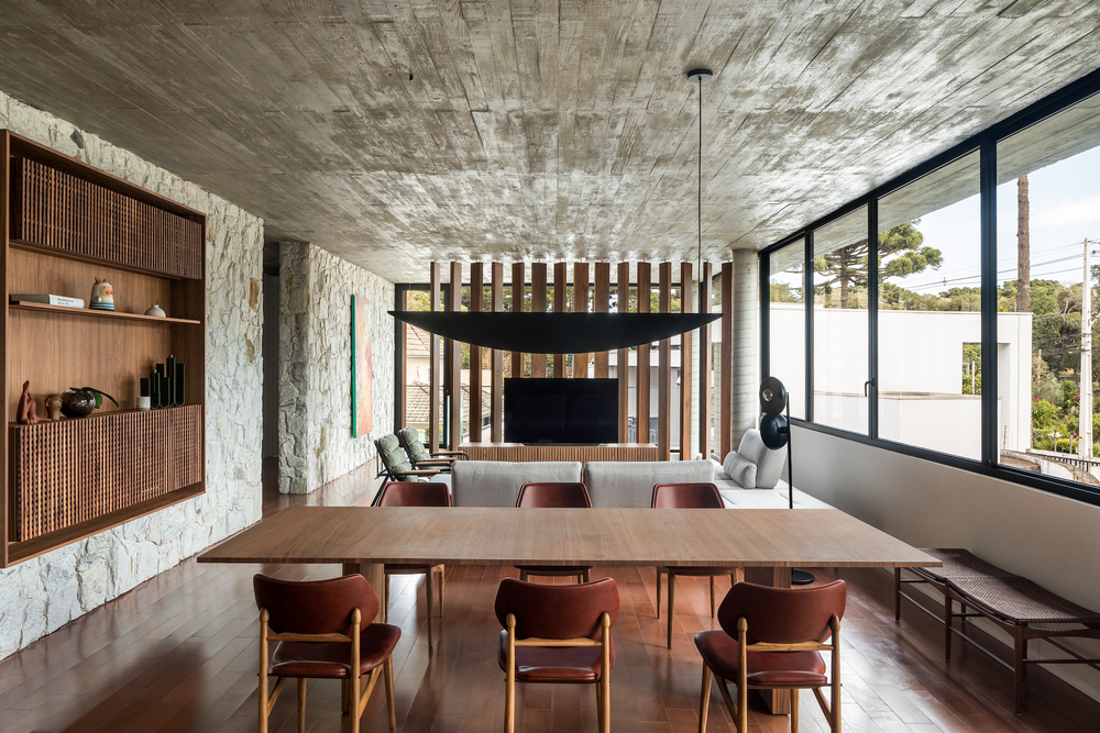 Casa dividida por parede de pedra aposta em materiais naturais