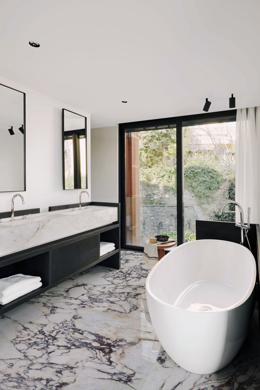 No banheiro amplo, os arquitetos exploraram mármores diversos e investiram em uma banheira de sobrepor — Foto: Fevzi Ondu