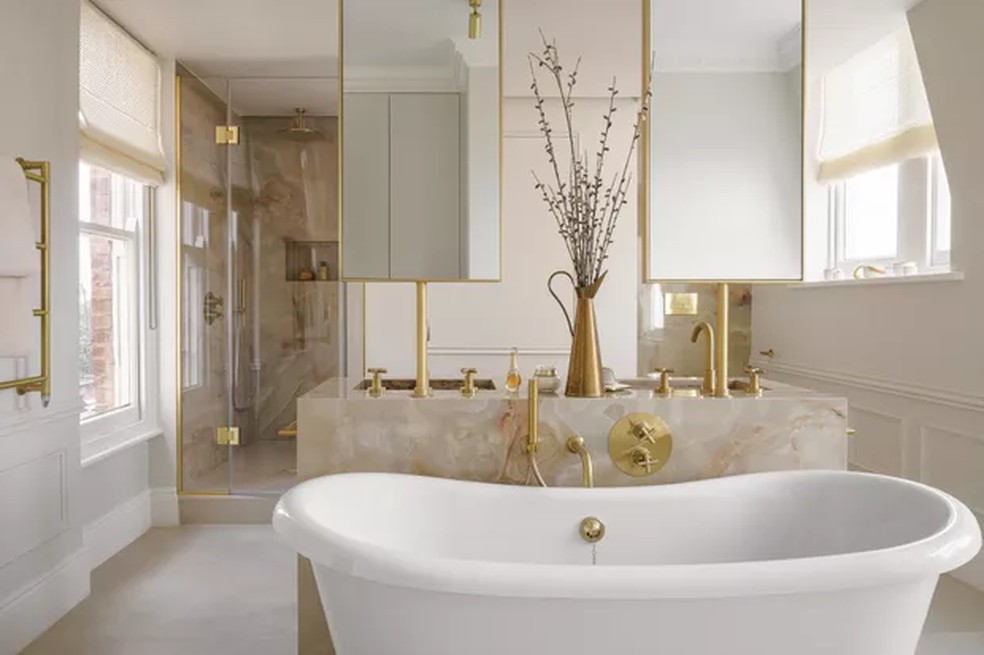 Além de cuba dupla, este banheiro conta com uma banheira e detalhes dourados. O projeto é da designer de interiores Theresa Obermoser — Foto: Vigo Jansons/Divulgação