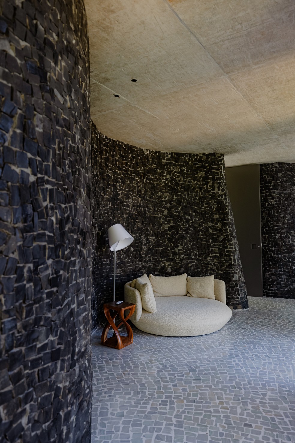 Este canto de leitura exibe a chaise baixa de Guilherme Wentz acompanhada da luminária de piso Melampo Floor, design Adrien Gardère para Artemide, na Iluminar — Foto: Luisa Lage