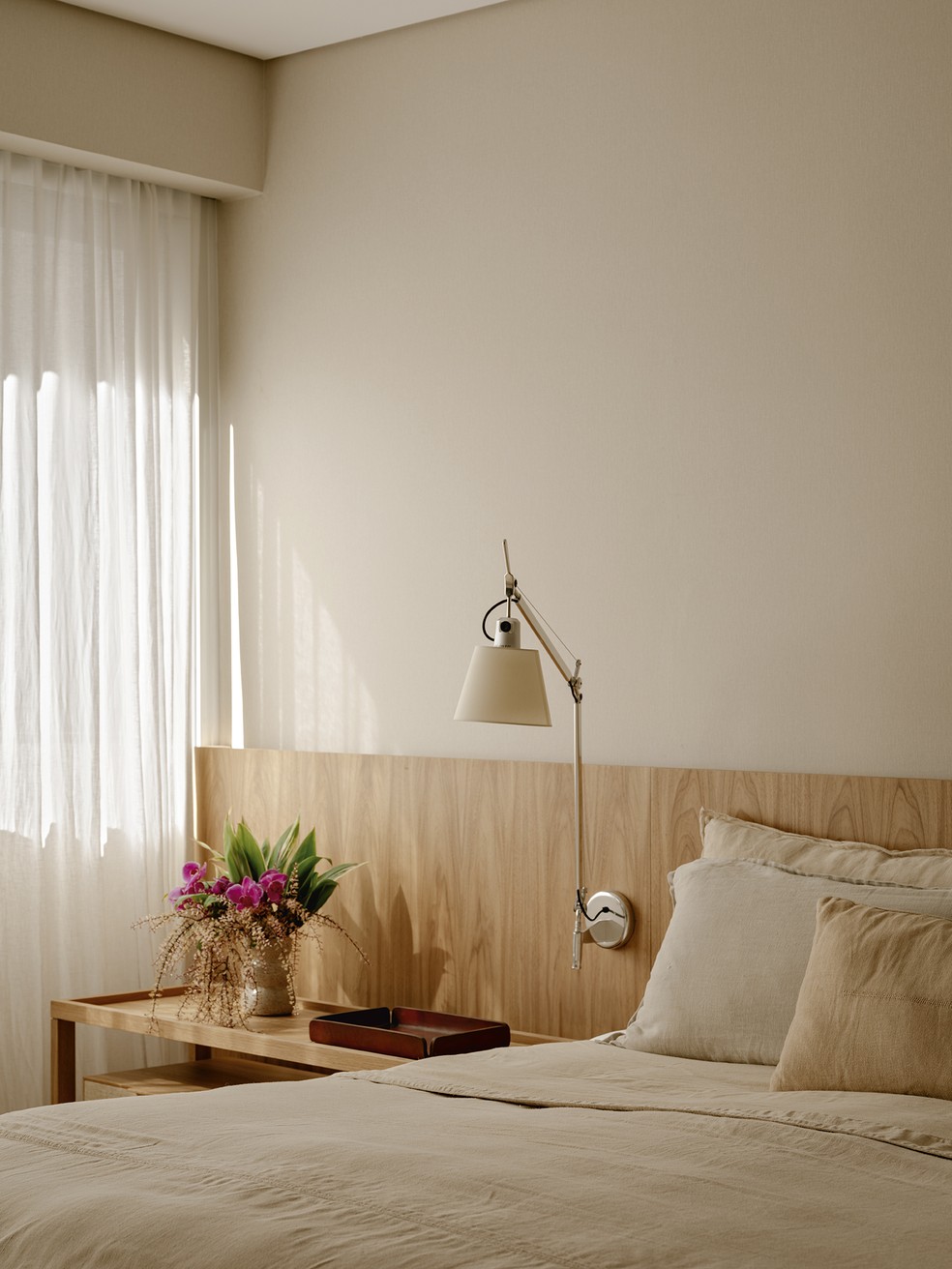O conceito de tons neutros e a variedade de texturas segue na área íntima, como no quarto equipado com cabeceira de madeira clara, desenhada pelo escritório, e luminária tolomeo, design Michele de Lucchi e Giancarlo Fassina para a Artemide, na Dimlux — Foto: Fran Parente