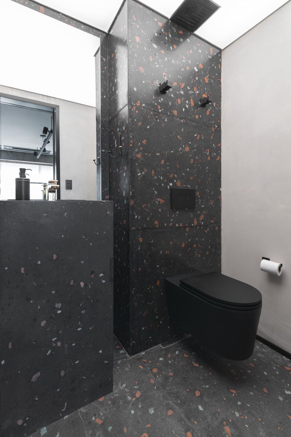 No lavabo, a arquiteta optou por um granilite escuro que se estende do piso às paredes — Foto: Cris Farhat