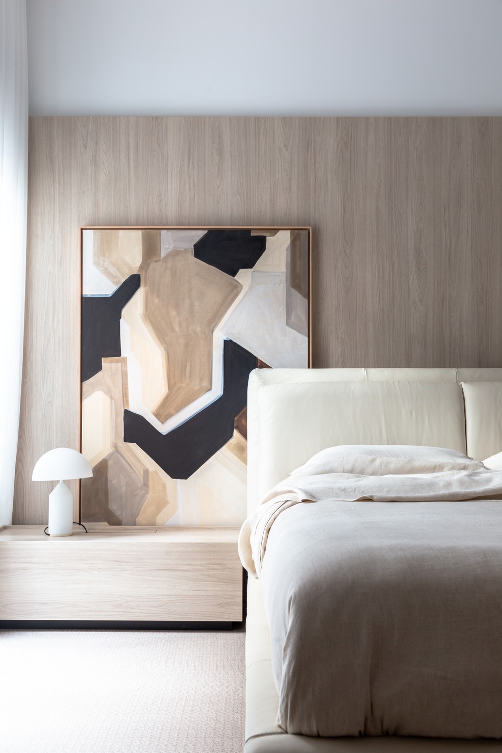 A suíte principal com atmosfera praiana recebeu cama Giunca LE07, da Natuzzi Editions, marcenaria da Ornnato Móveis em MDF Carvalho Berlin, da Duratex, luminária de mesa Atollo, de Vico Magistretti para Oluce, na loja A de Arte BH, e tela da Tom sobre Tom. O tapete é da By Kamy e a roupa de cama é da Zara Home  — Foto: Marilia Ganassin