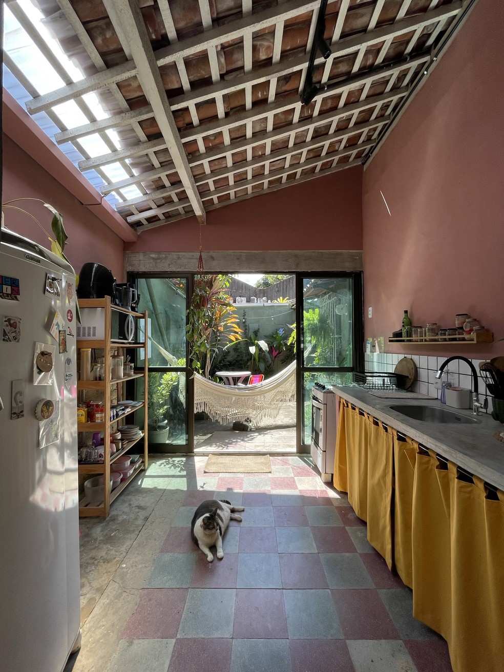 O ambiente da cozinha ficou integrado ao jardim e ganhou uma bancada de concreto — Foto: Karla Burlamaqui