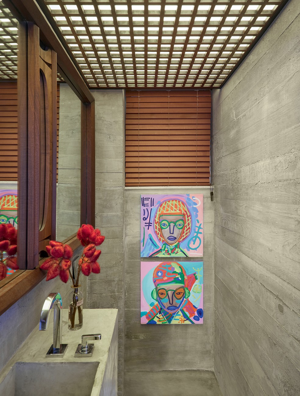No lavabo, revestido de concreto, espelho comprado num antiquário de Nova York e duas telas de Rimon Guimarães — Foto: André Klotz