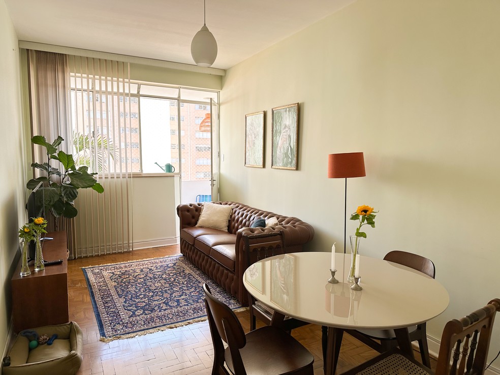 A sala de estar do apartamento conta com sofá, mesa para refeições e acesso à varanda  — Foto: Monique Forner