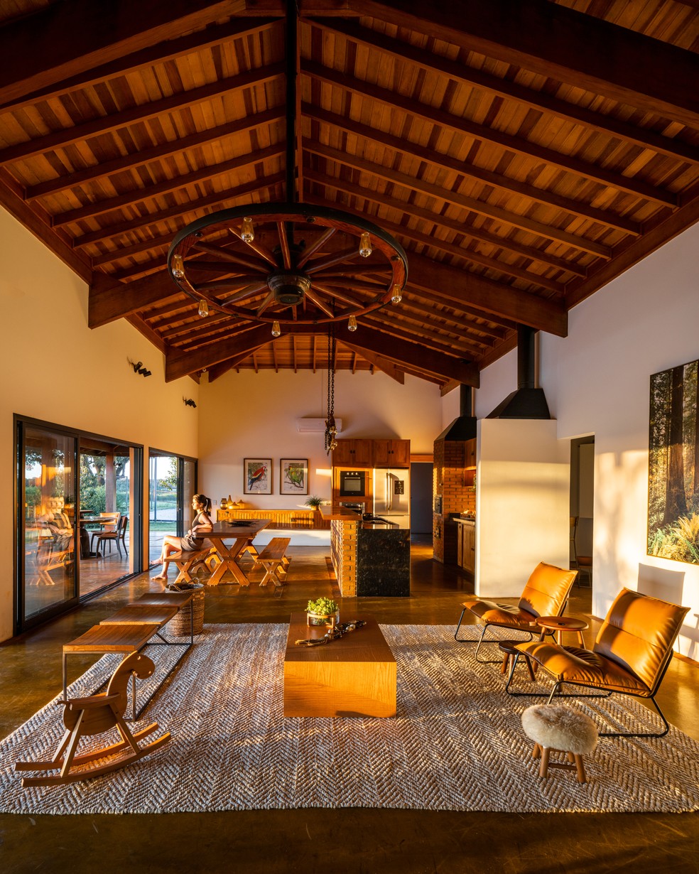 Em casa de campo, sala de estar e churrasqueira se unem em um ambiente só - valorizado pela luz do pôr do sol  — Foto: Manuel Sá