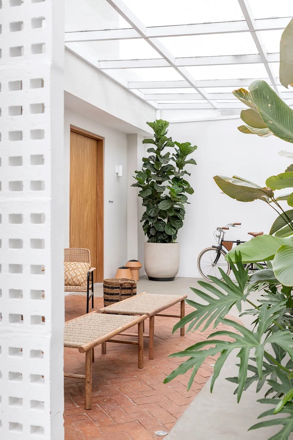  Jardim com plantas, piso de tijolos e de cimento queimado e banco para relaxamento em projeto do estúdio Voa Arquitetura  — Foto: Rafael Renzo/Divulgação