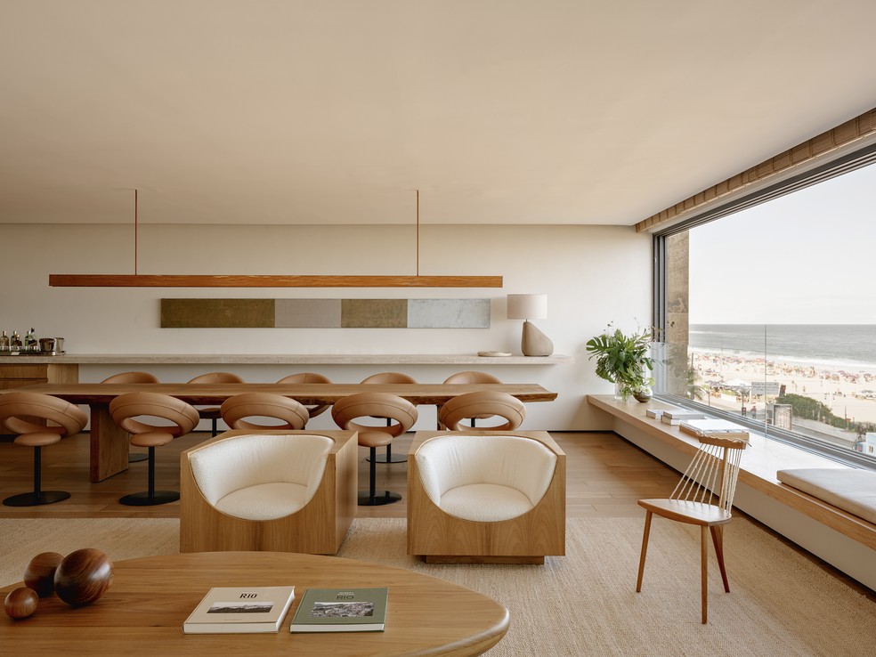 Este ângulo do living revela a integração com a sala de jantar, onde se destacam tela de Sérgio Sister, na galeria Nara Roesler, luminária pendente desenvolvida pelo Bernardes Arquitetura com a Lightworks e, sobre o aparador, abajur Sinatra, design Arthur Casas para o Studio Objeto      — Foto: Fran Parente