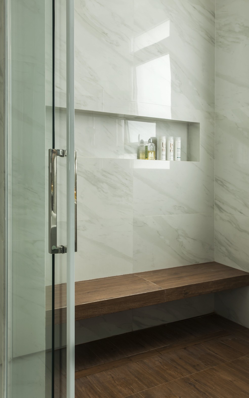 Assinado pelo escritório Korman Arquitetos, esse banheiro junta o amadeirado e a pedra marmorizada — Foto: Divulgação
