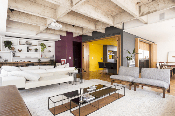 Neste apartamento, o tom de roxo do living complementa o amarelo da cozinha quando as portas se abrem. Projeto de Mestisso Arquitetura  — Foto: Ricardo Bassetti