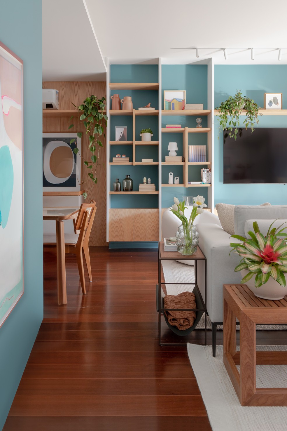 A cor azul das paredes na sala de estar aparece no hall de entrada e vai até a estante da televisão — Foto: Lilia Mendel