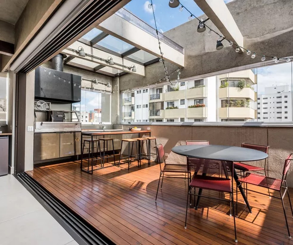 Varanda gourmet com piso de madeira em projeto conduzido pelo escritório Mandarina Arquitetura — Foto: NATHALIE ARTAXO / DIVULGAÇÃO