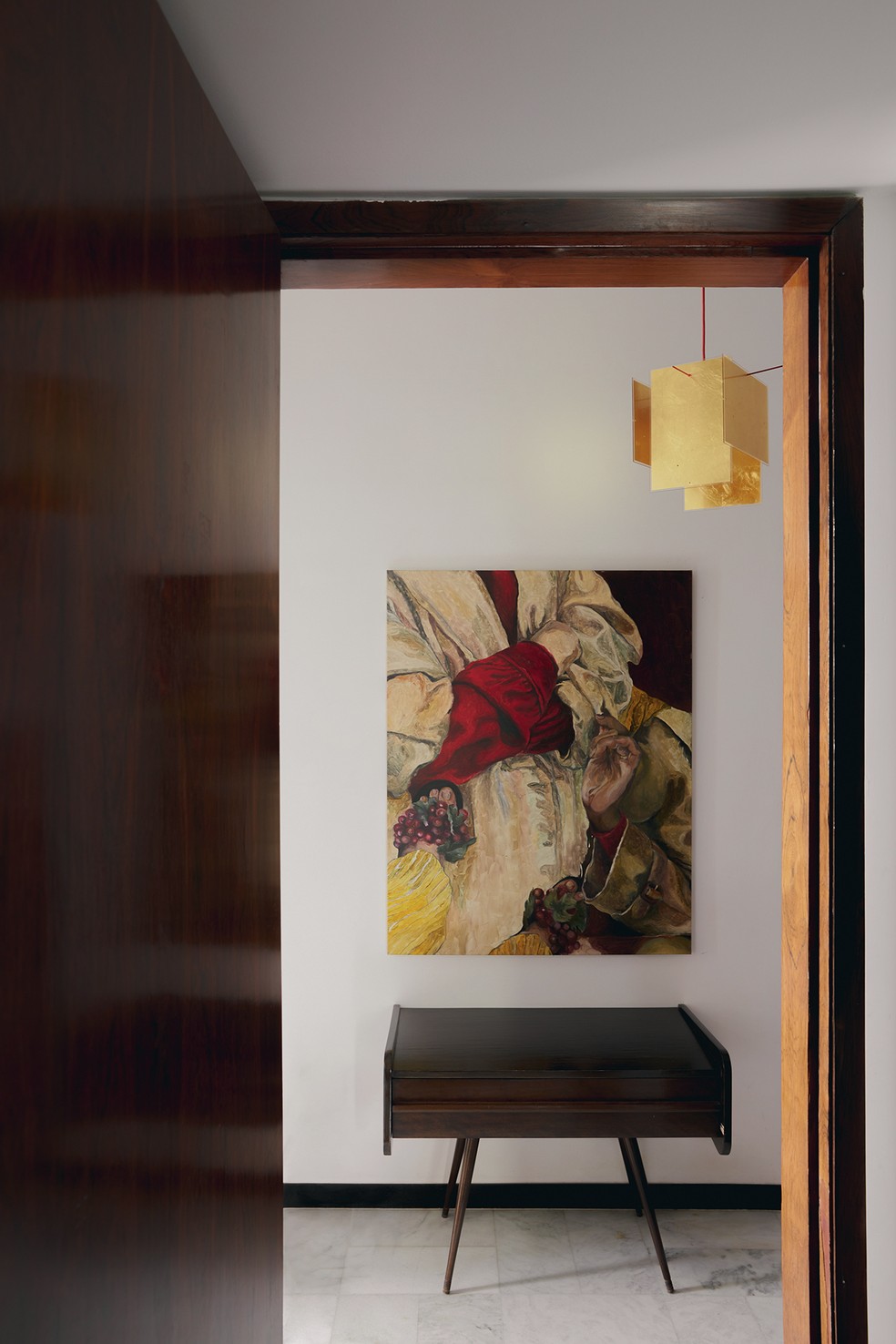 Detalhe da circulação dos quartos revela mesinha vintage e, na parede, pintura de Giulia Puntel, tudo sob pendente 24 Karat Blau, de Ingo Maurer, comprado em Nova York — Foto: Luiza Ananias