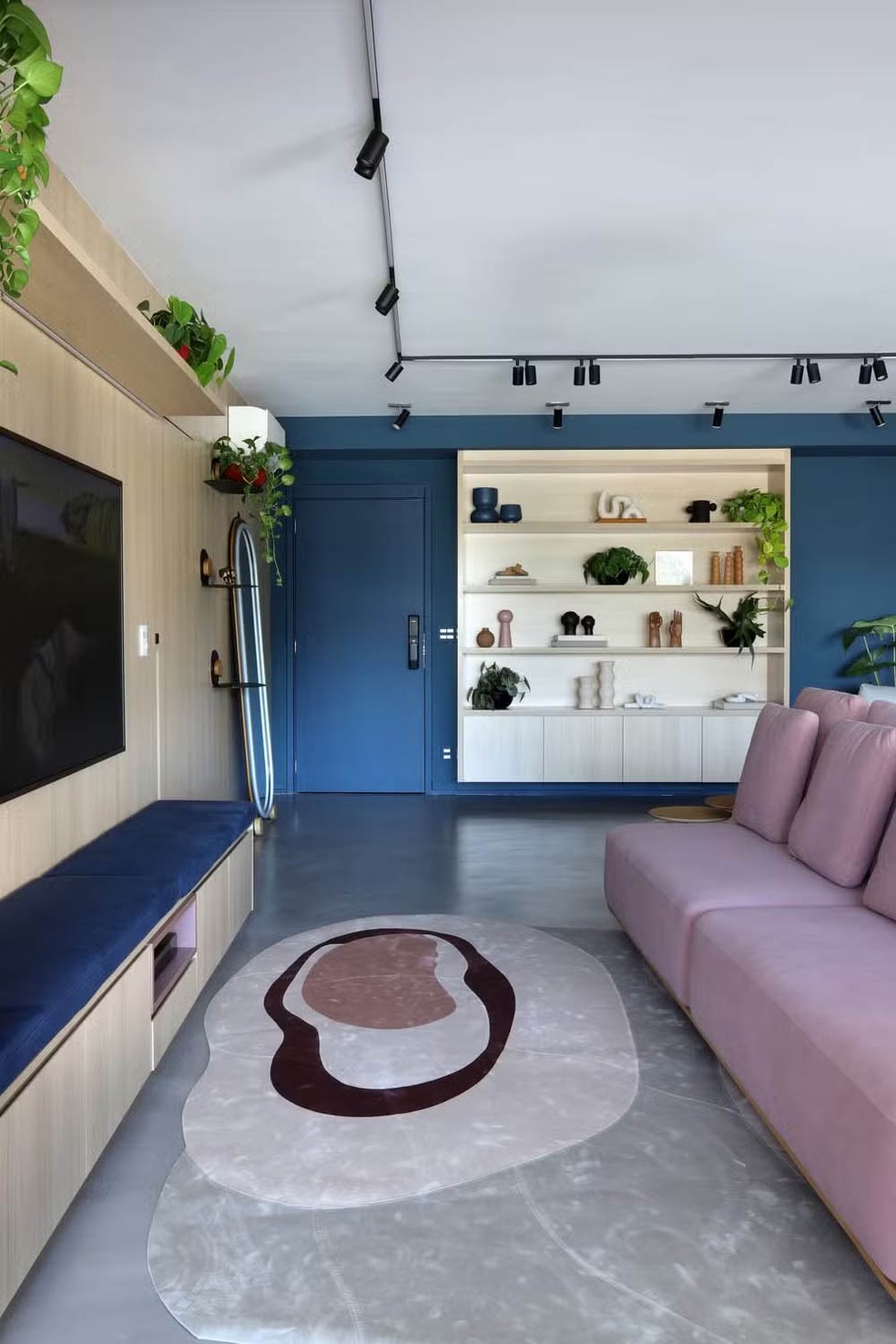 Neste apartamento em São Paulo, o azul demarca a área da entrada, onde até a porta recebeu a cor  — Foto: Mariana Orsi