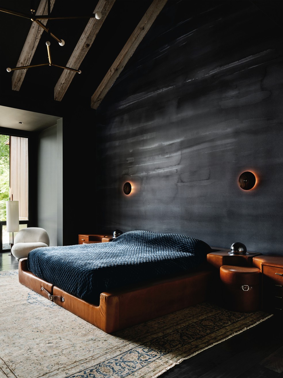 Pé-direito alto propicia amplitude para o quarto com a parede preta e móveis de couro — Foto: Chase Daniel