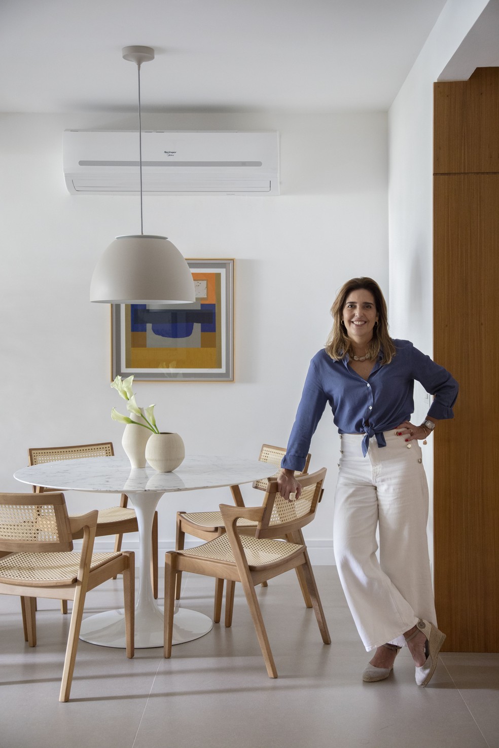 A arquiteta Fernanda Medeiros, responsável pelo projeto, posa apoiada na mesa de jantar — Foto: Juliano Colodeti/MCA Estúdio
