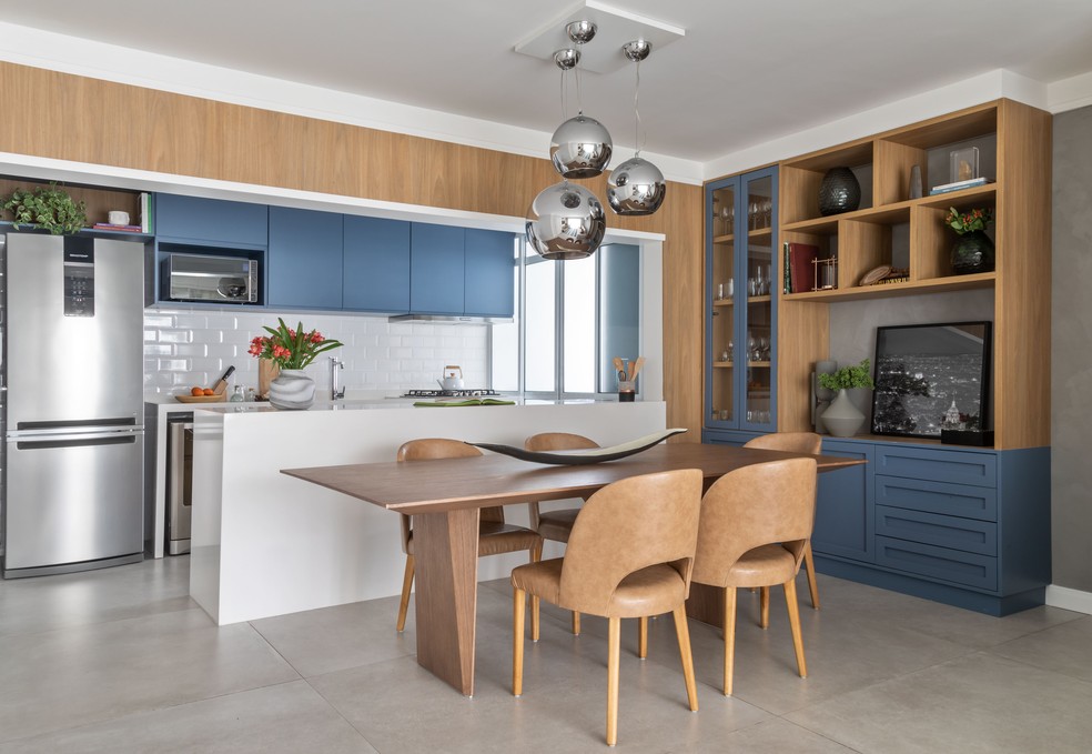 Neste projeto do escritório MSAD Arquitetura, o living integrado com a cozinha ganhou uma mesa de madeira — Foto: Evelyn Müller