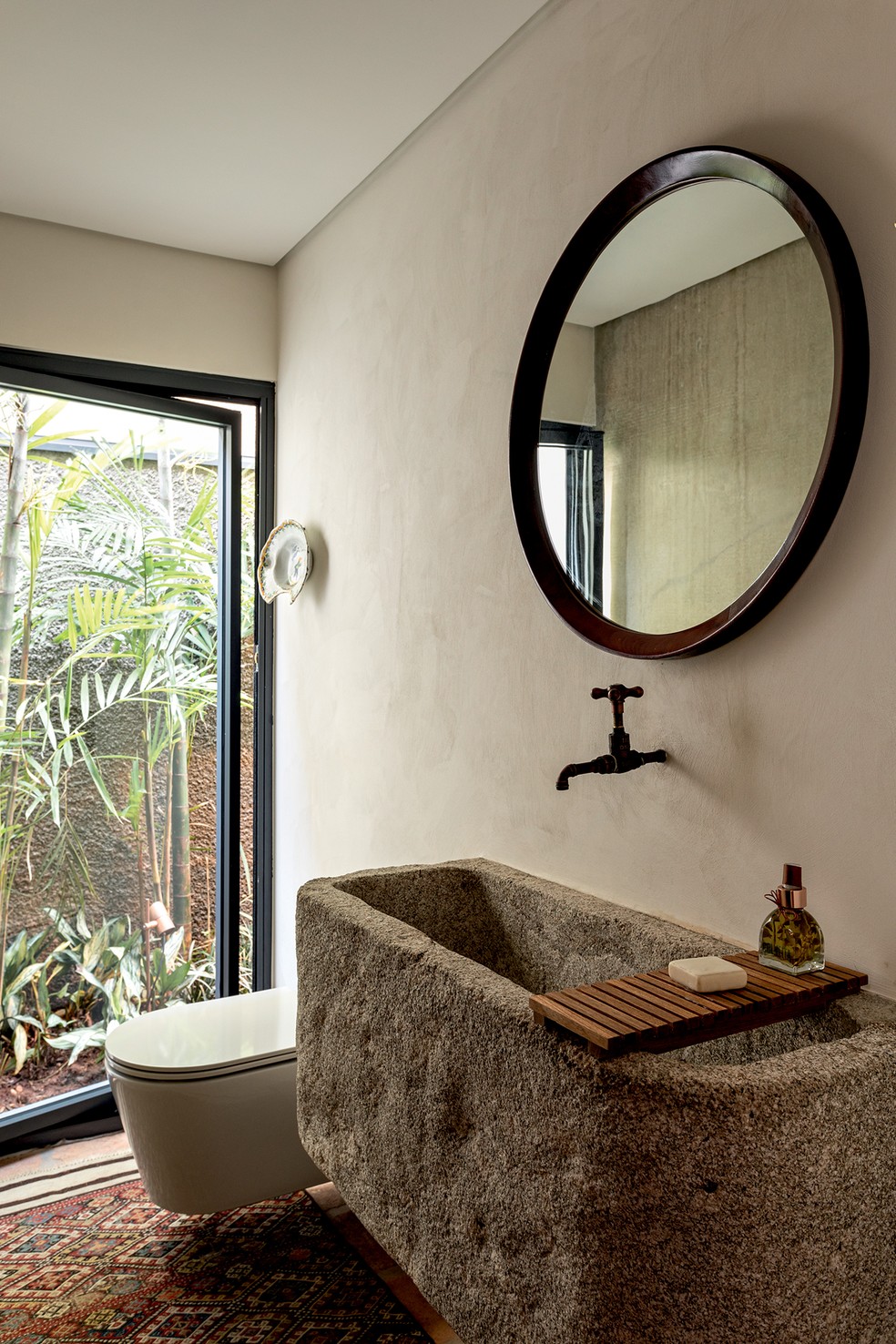 O banheiro  ganhou cuba esculpida em  pedra-sabão pela Pagliotto, acompanhada de espelho vintage — Foto: Fran Parente