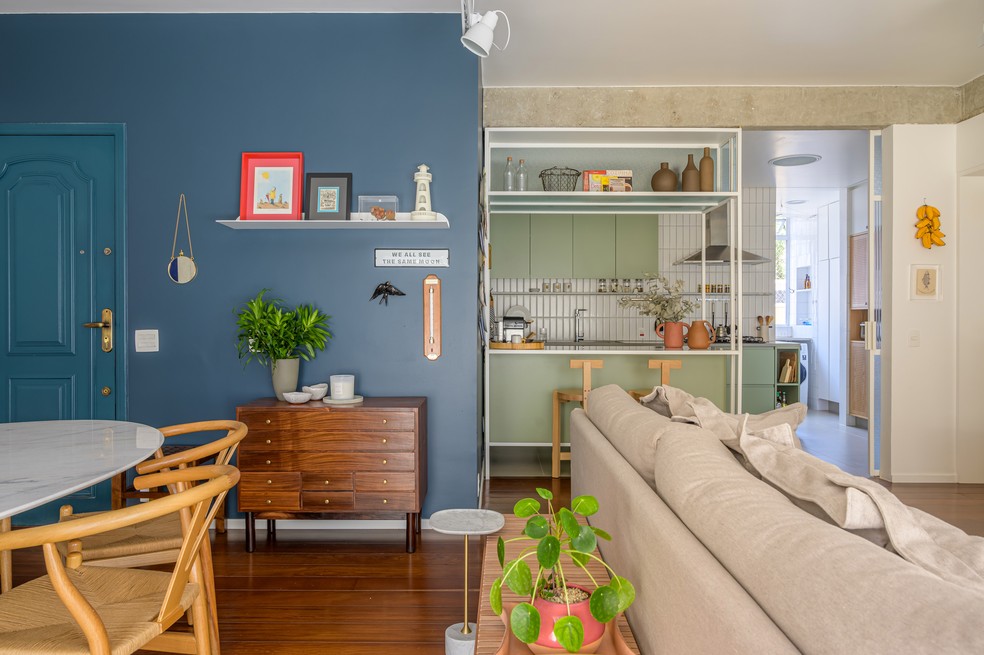 Já a parede, que interliga a sala de estar e a cozinha, foi pintada na cor azul-marinho — Foto: Sambacine
