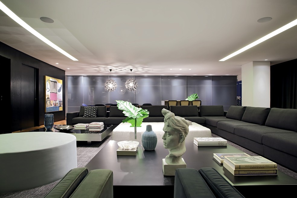 O amplo living  integrado reúne estar, escritório e área  gourmet, com uma seleção de mobiliário  de linhas minimalistas — Foto: Divulgação