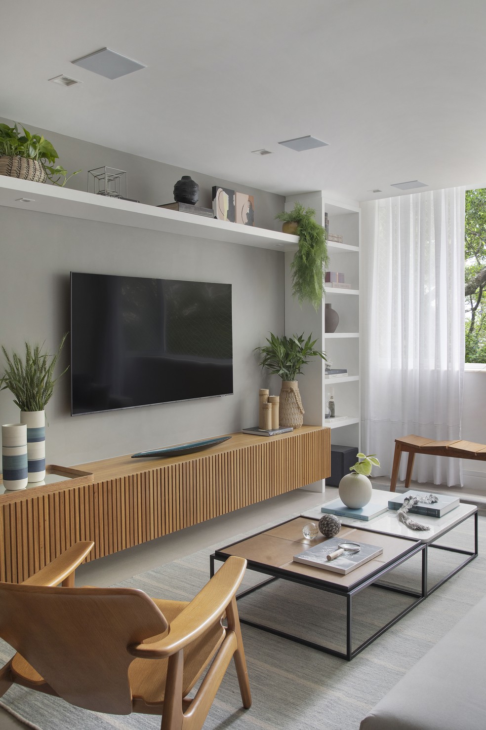 A sala de TV revela que a madeira é um dos principais elementos do décor do apartamento — Foto: Juliano Colodeti/MCA Estúdio