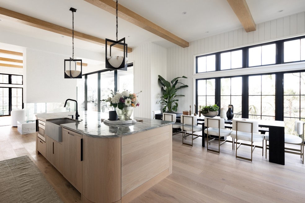 Cozinha com ilha e sala de jantar são emolduradas pelas janelas amplas em casa na Carolina do Norte — Foto: Air Design Photography