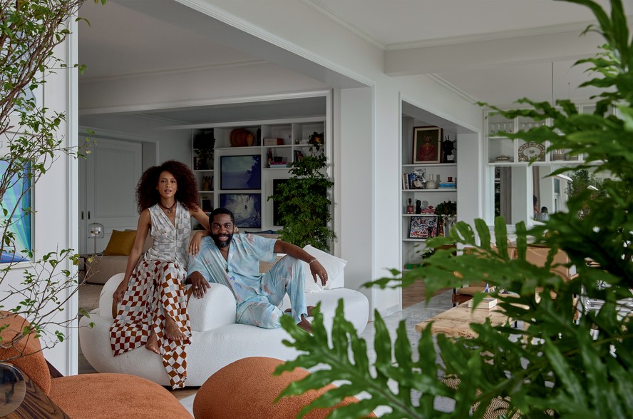 Tas, de vestido Lenny Niemeyer e colar Sauer, e Lzaro, de camisa e cala Handred, pulseira Skull e colar Silvia Furmanovich, posam no sof-ilha Desejo, design Luisa Moyss para a Breton