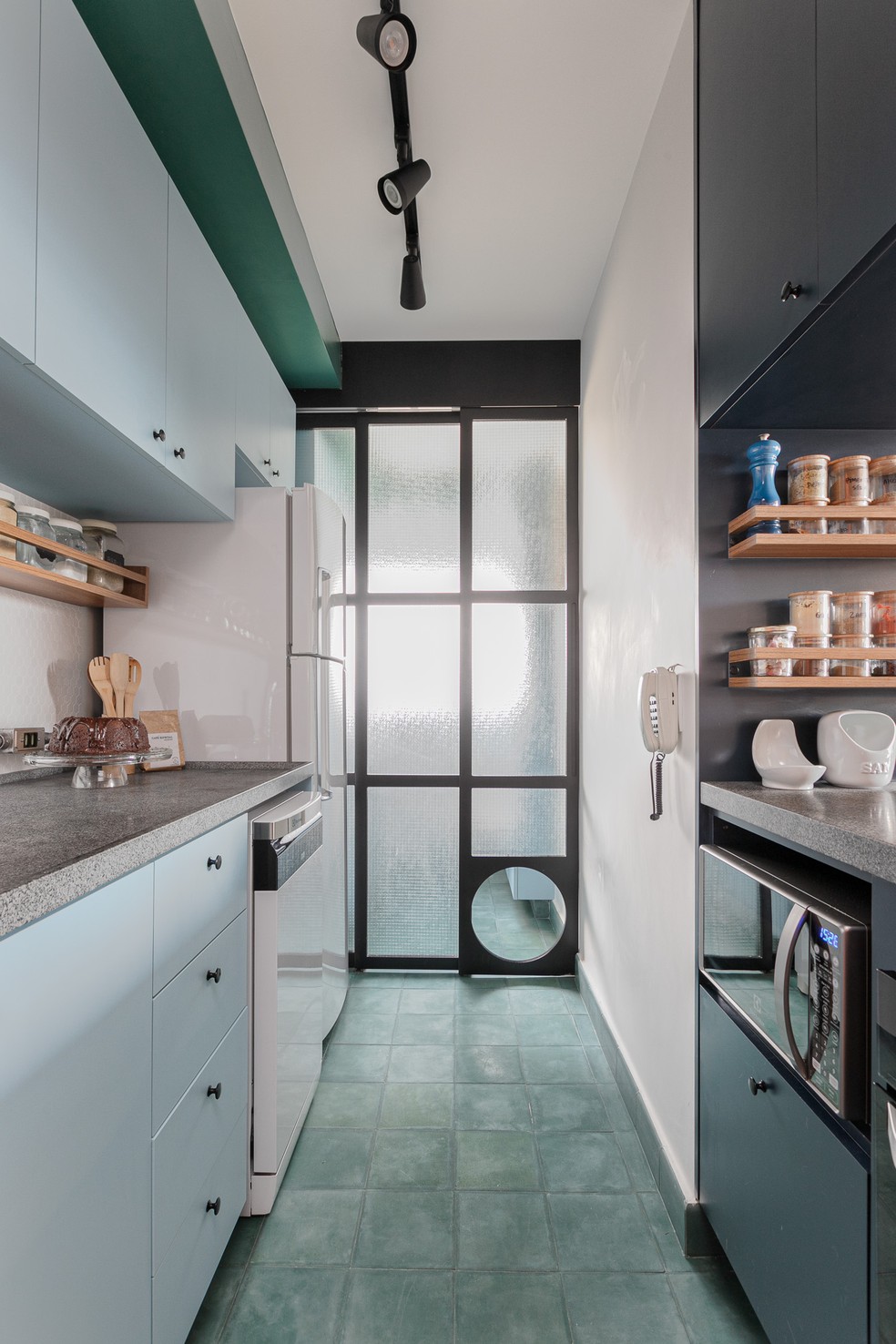 Neste ângulo da cozinha-corredor, observa-se o acesso para a lavanderia, isolada por portas de vidro — Foto: Gisele Rampazzo