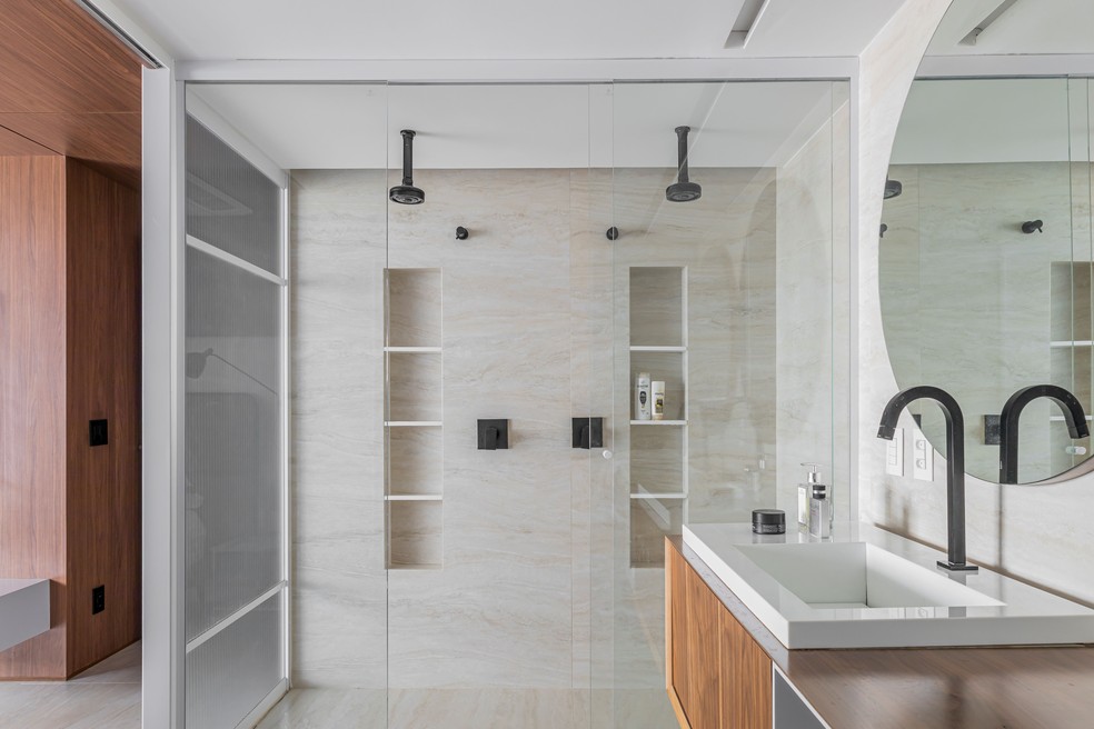Amplo, o banheiro da suíte principal conta com dois chuveiros e fica isolado por painéis de vidro canelado — Foto: Felipe Petrovsky