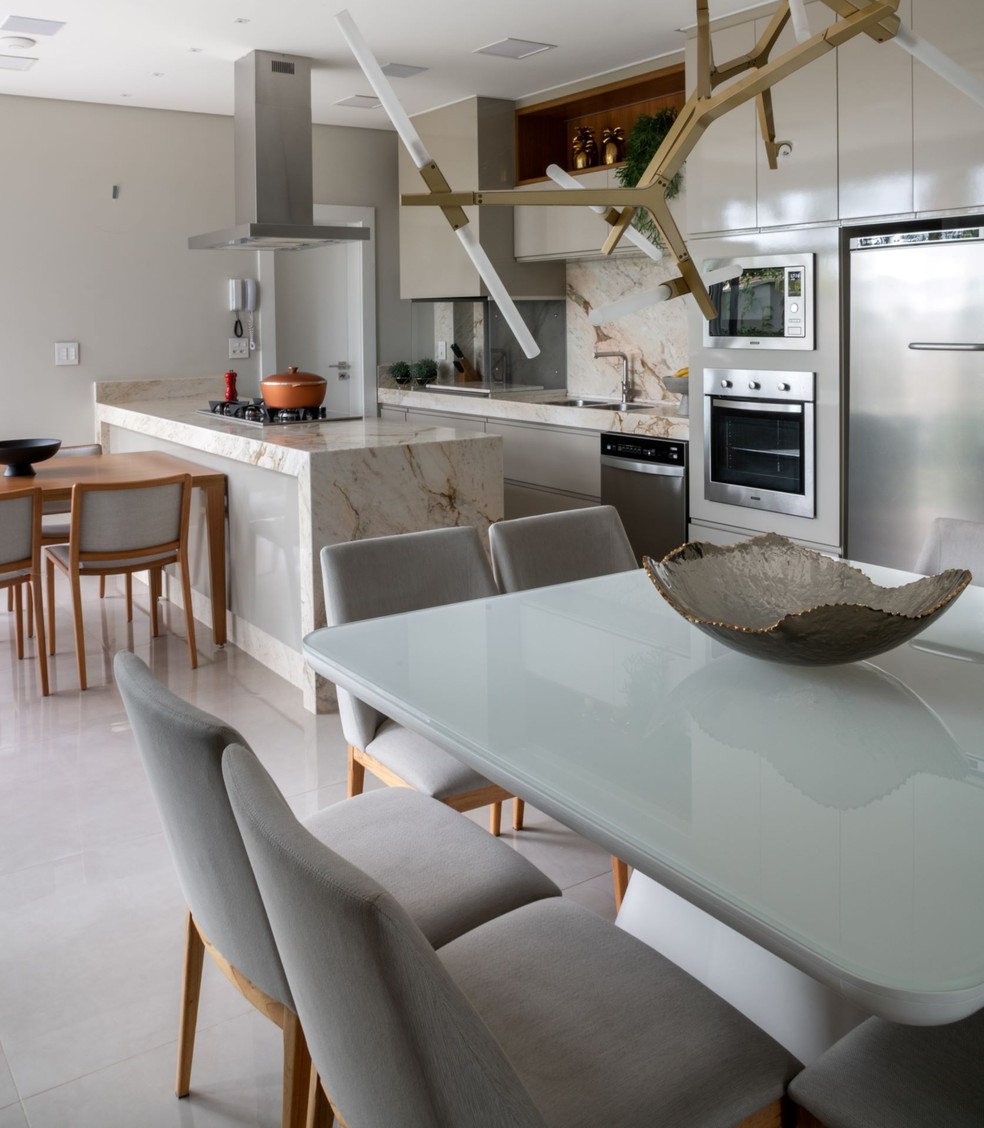A arquiteta Laura Pezolato elegeu a bancada de mármore branco como base para a decoração da cozinha integrada com a sala de jantar, que tem uma paleta de cores neutra, com branco e fendi — Foto: Fávaro Jr.
