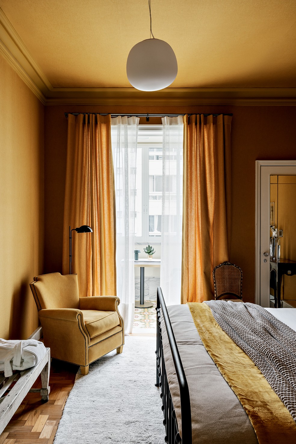 As cortinas da Uniflex separam quarto e varanda, e a poltrona da Jocal Móveis e Estofados foi revestida com o mesmo tom das paredes — Foto: Fran Parente