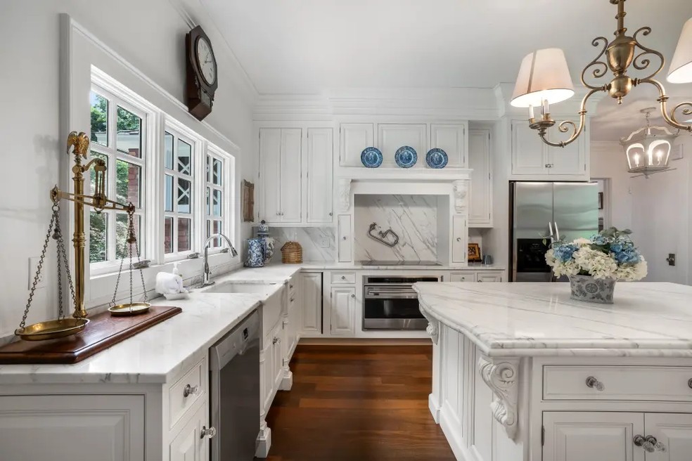 Cozinha, com móveis de madeira em branco, além de bancadas e azulejos marmorizados — Foto: Divulgação/Matthias Marklin da VistaBee Photography