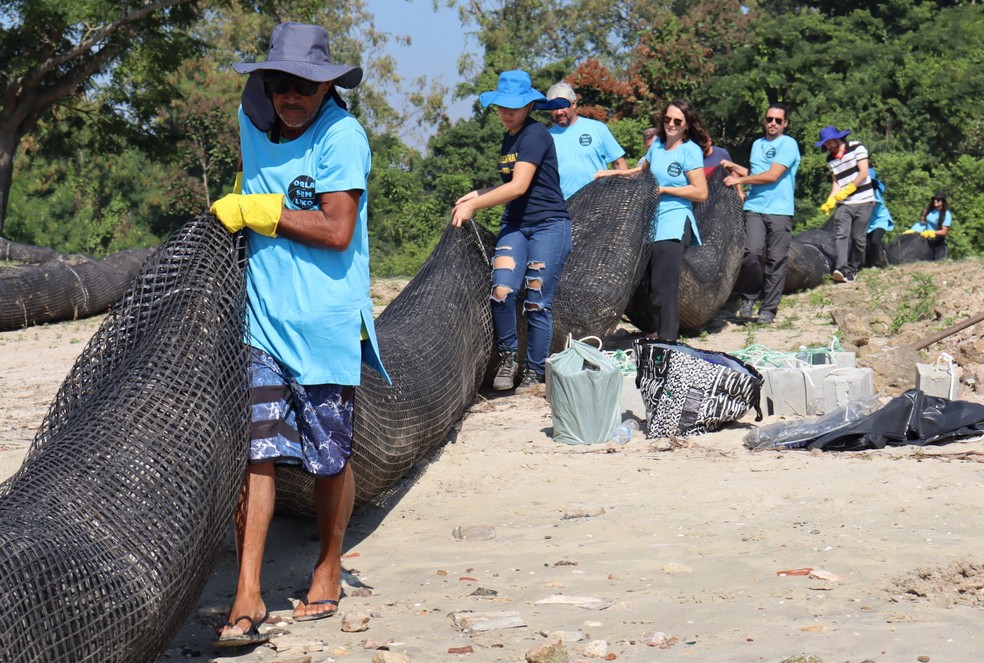 Integrantes do Orla sem Lixo levando a barreira para a água — Foto: Ana Vitória Villar/Divulgação