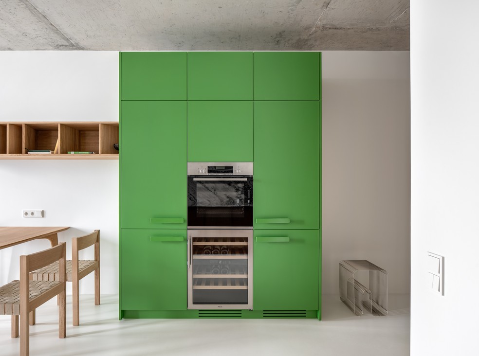 Na cozinha aberta, a marcenaria sob medida verde chama a atenção com fogão e adega embutidos — Foto: Andrey Bezuglov