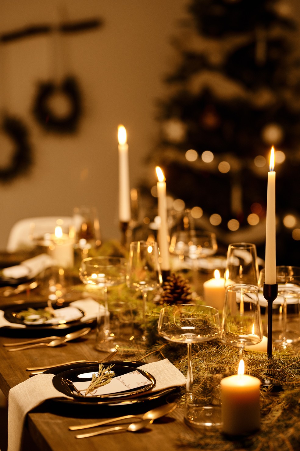 Mesa de jantar para a ceia de Natal com velas e objetos decorativos, como plantas e pinhos — Foto: Nicole Michalou/Pexels