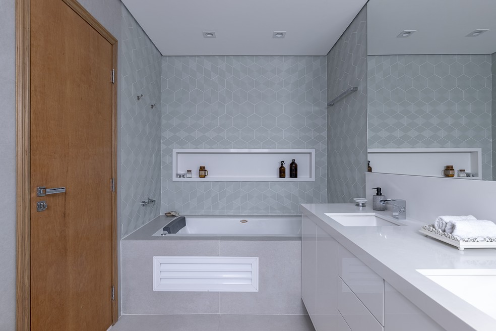 Banheiro projetado pela arquiteta Ju Matos, com o revestimento verde para trazer toda a diferença e o largo nicho em pedra branca — Foto: Rafael Renzo