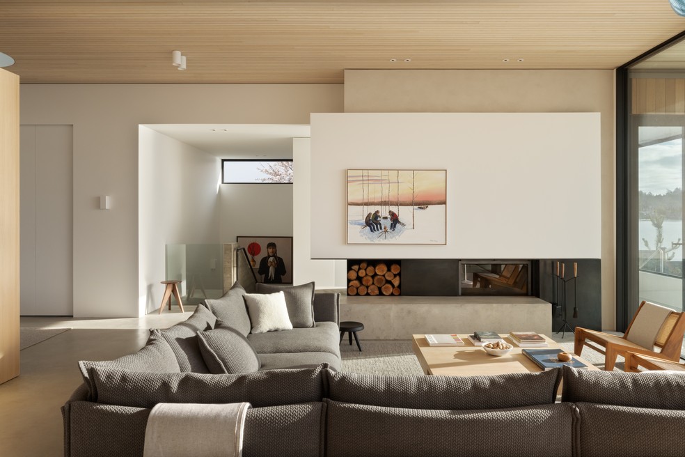 Na sala da lareira, a cartela de cores neutra e as texturas garantem o clima de aconchego dos interiores — Foto: Ema Peter