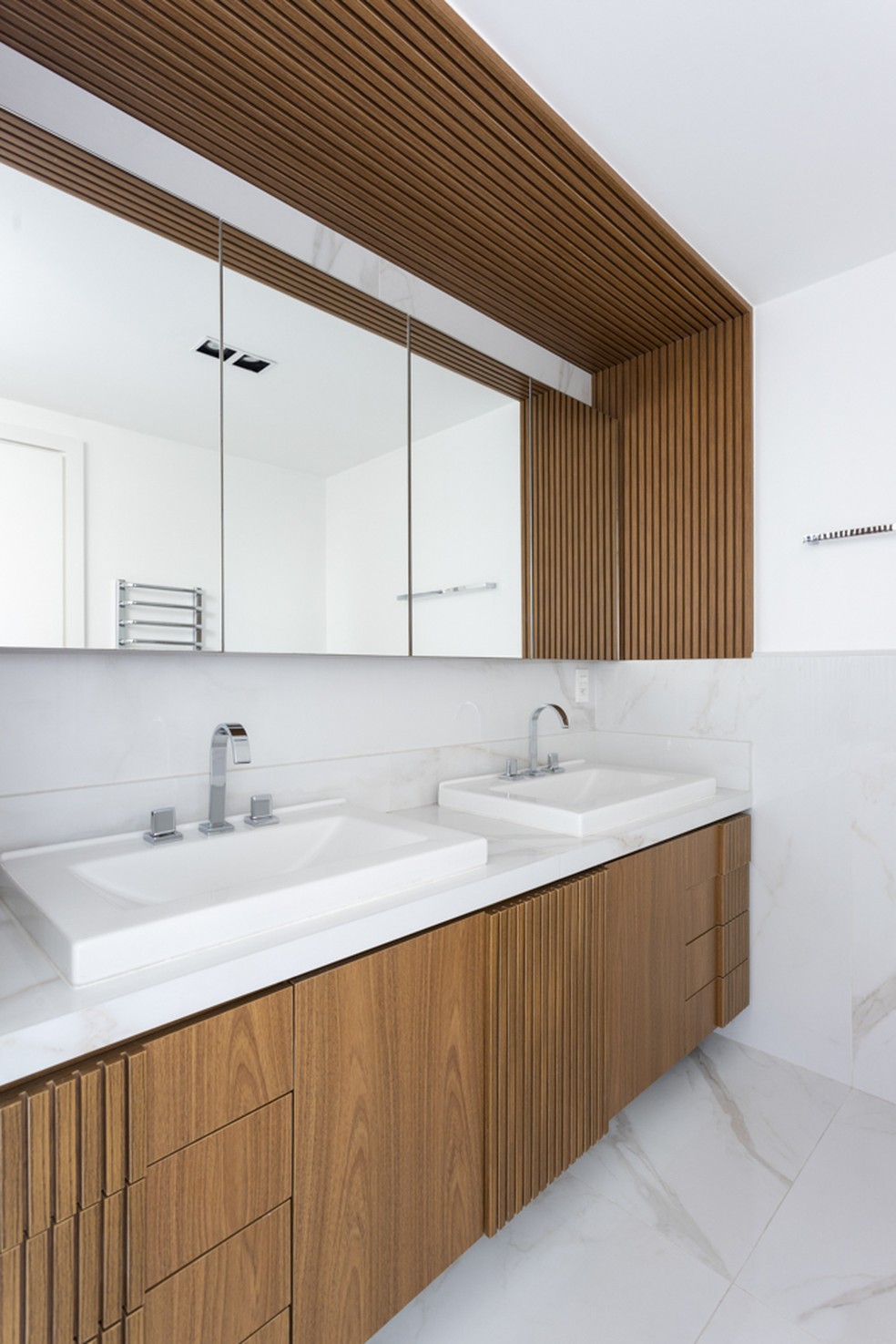 Ainda no banheiro, o porcelanato marmorizado cobre o piso e a bancada dupla — Foto: Thiago Travesso